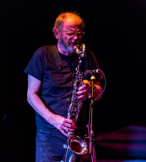 Jazzmusiker spielt Saxophon unter blauem Bühnenlicht.